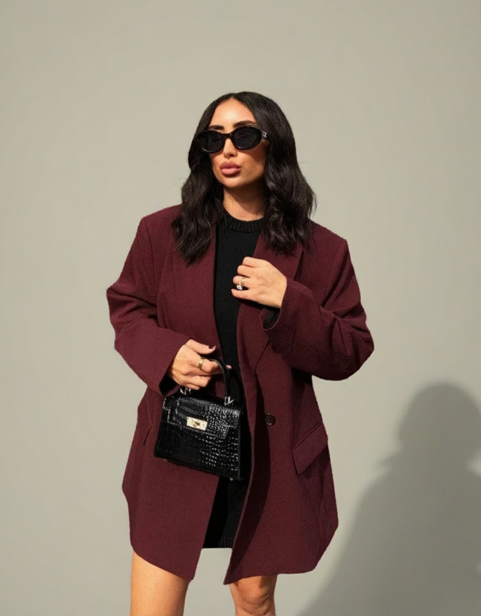 Blazer femme bordeaux vintage porté avec une robe noire et un sac à main élégant