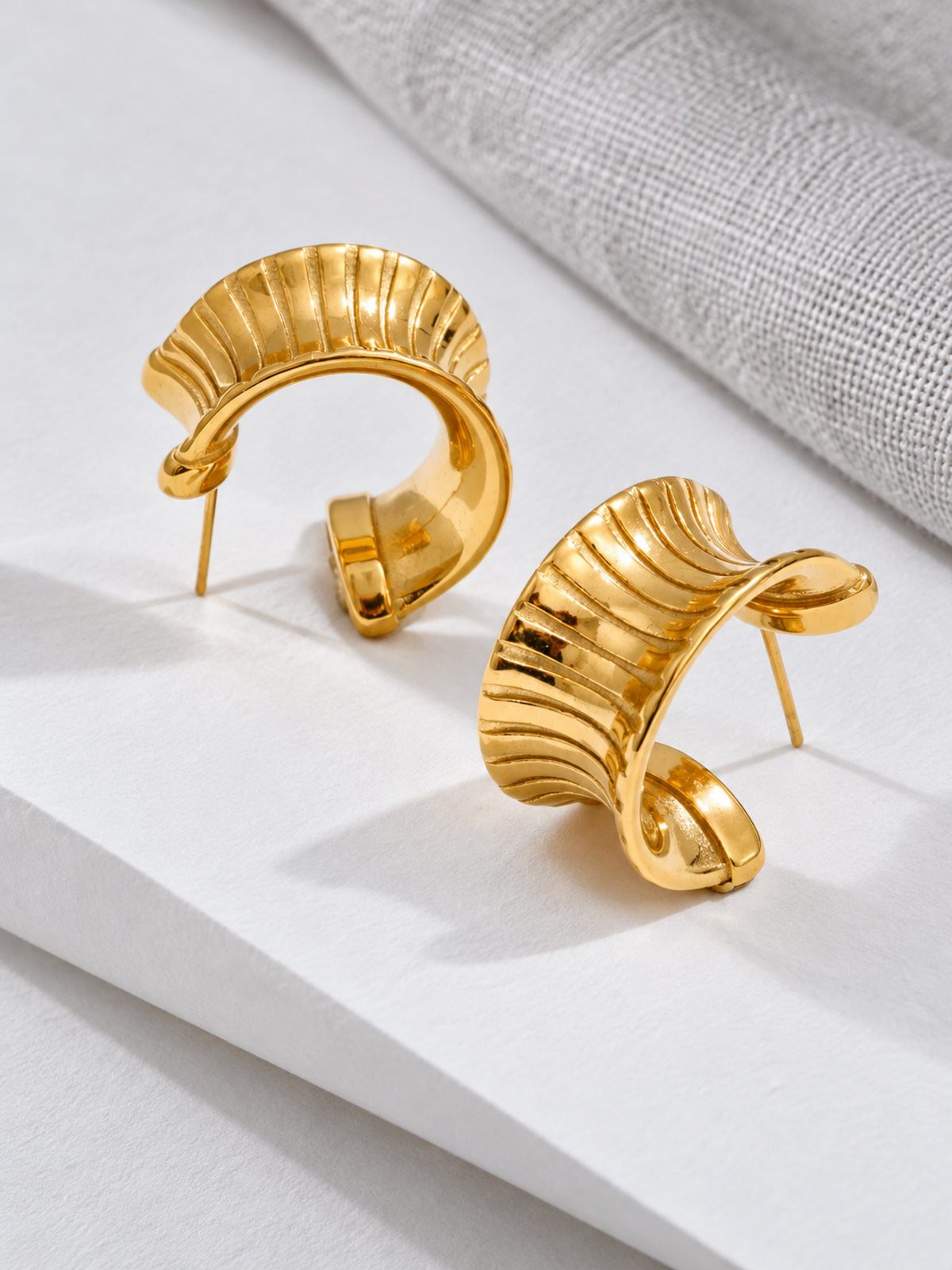 Cleo Huggie Earrings — editorial still life
