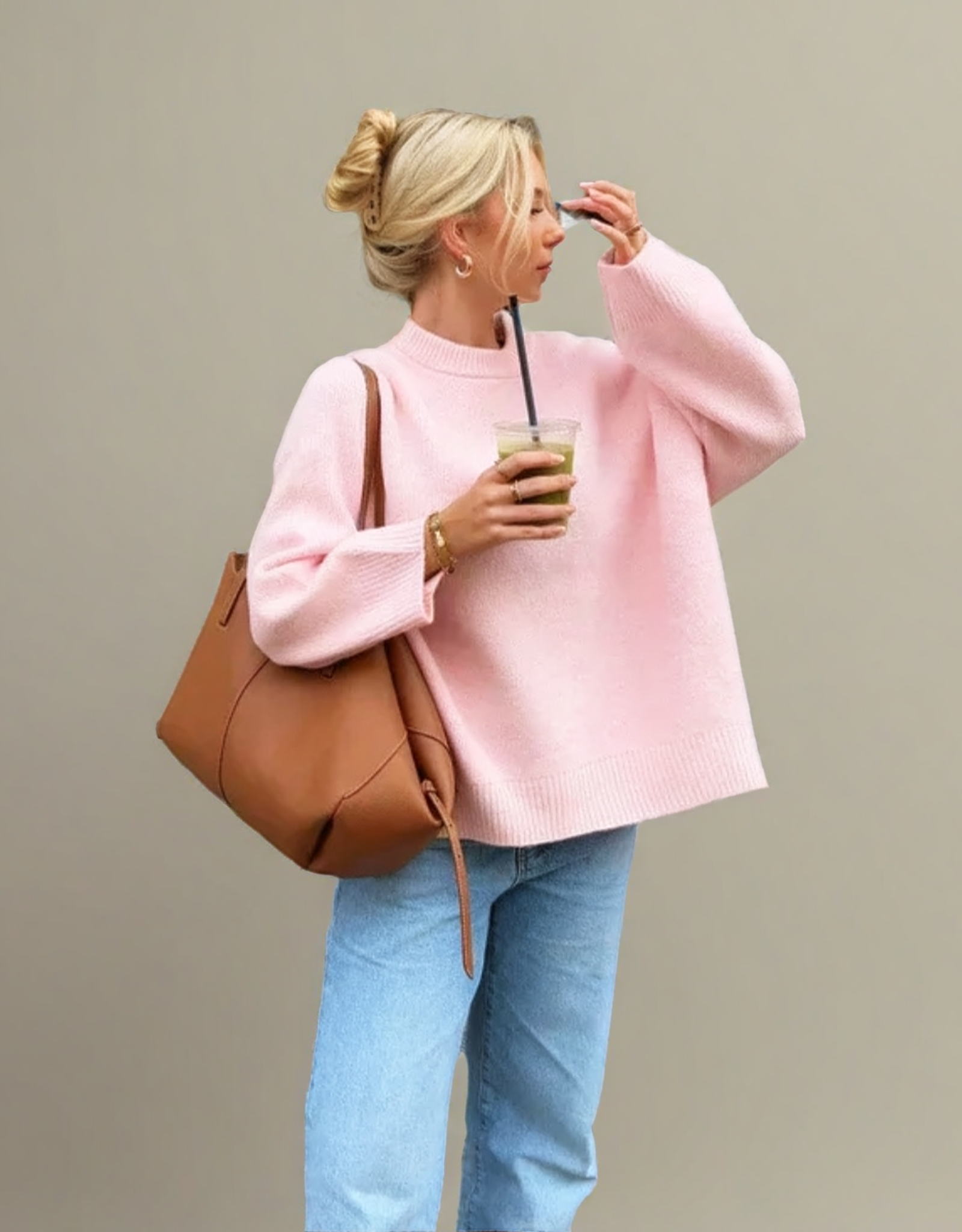 Pull rose Fondelier à manches larges avec un sac en cuir marron et un verre de café