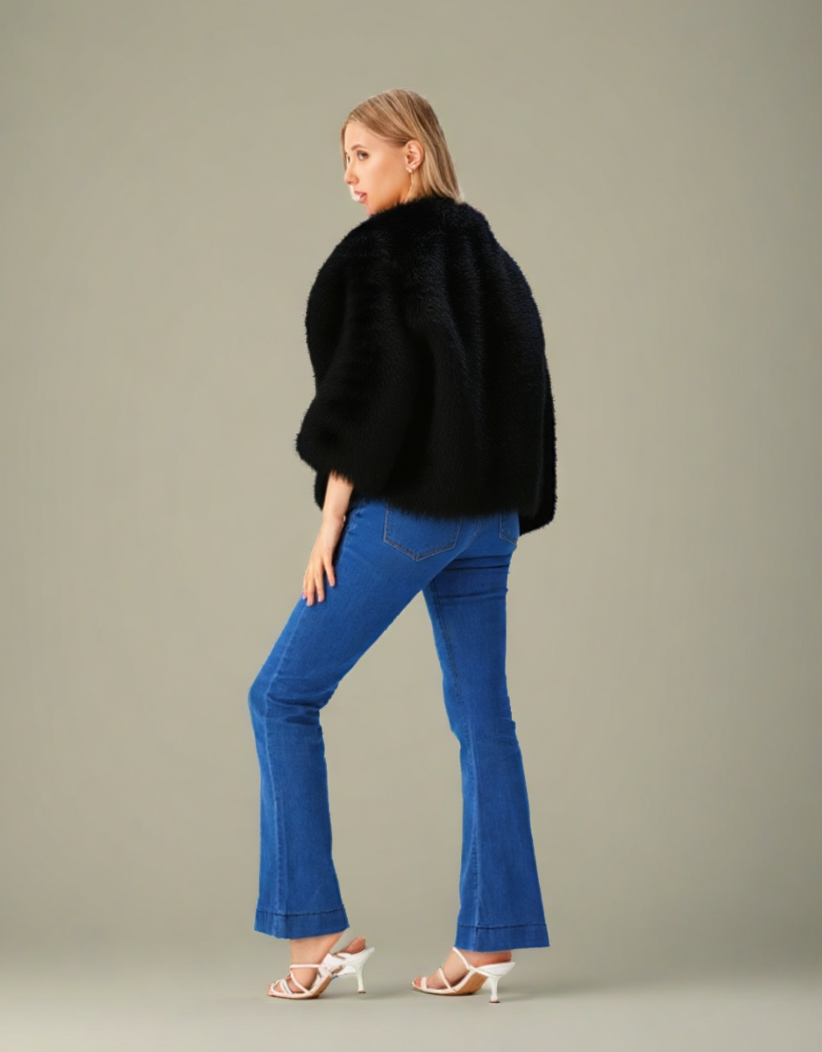 Veste courte fausse fourrure femme en noire, portée avec un pantalon bleu et des sandales blanches